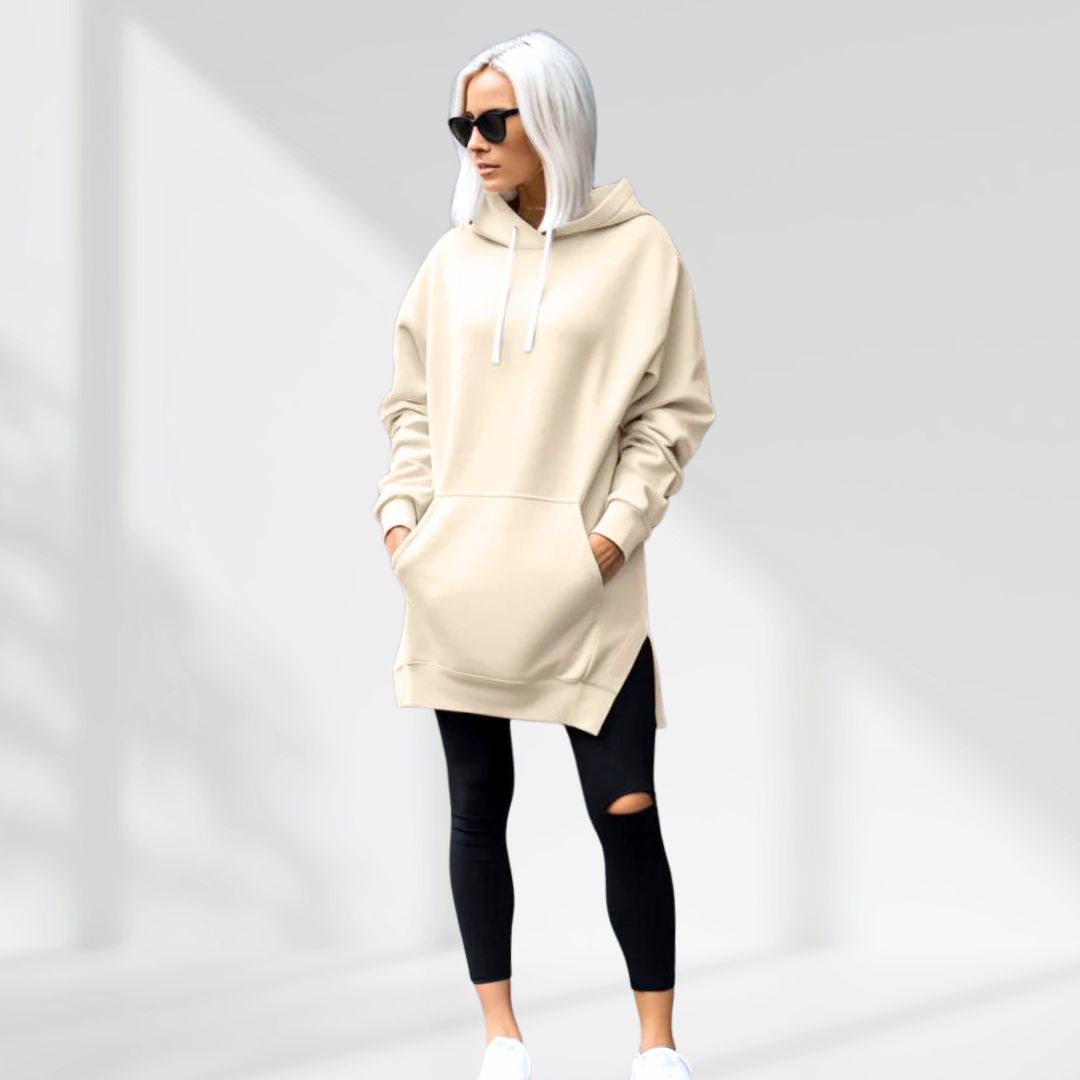 Woman wearing a cream hoodie dress, standing and facing forward to show the fit and style.